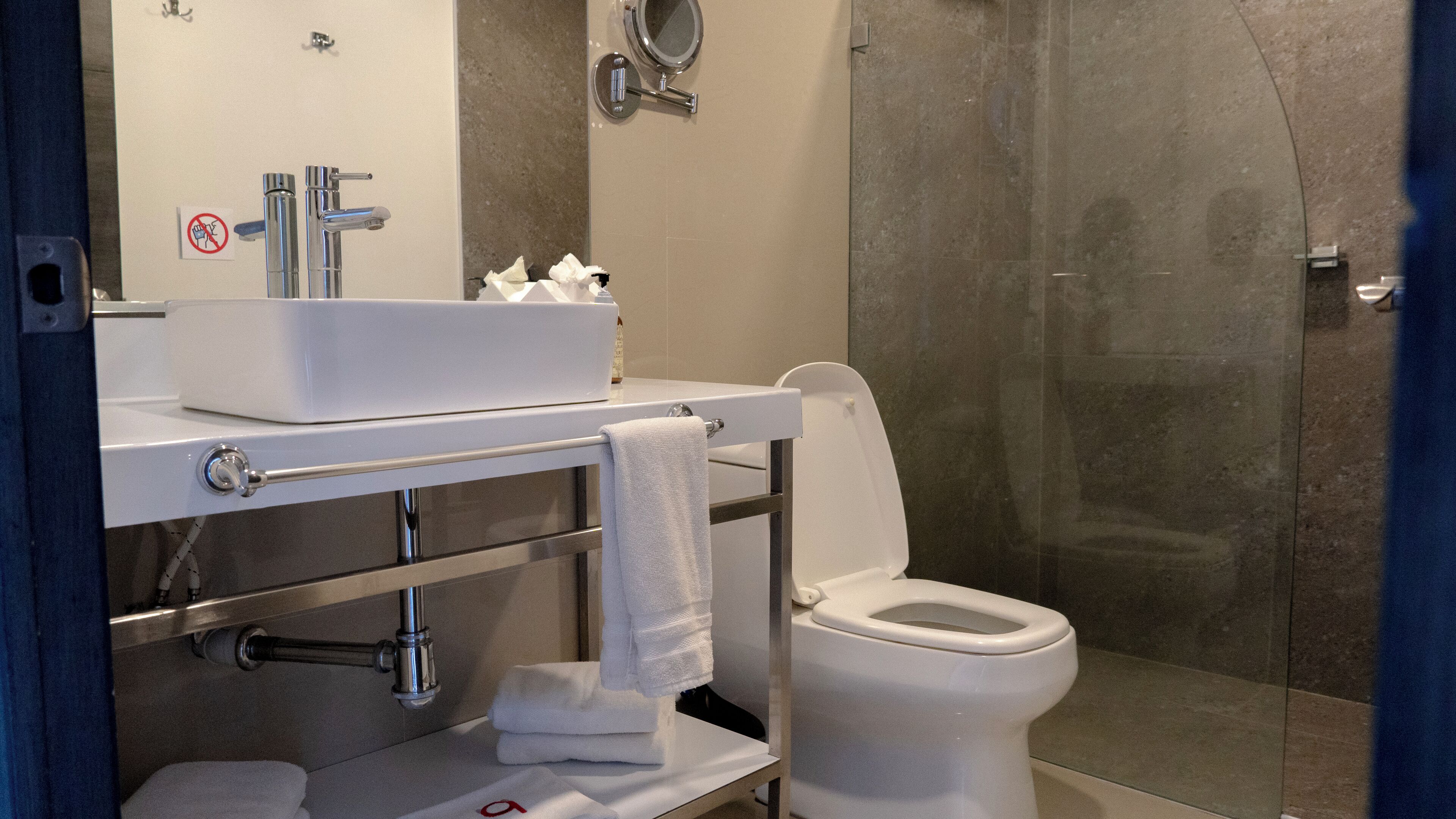 A modern bathroom with a white sink, mirror, and toilet.
