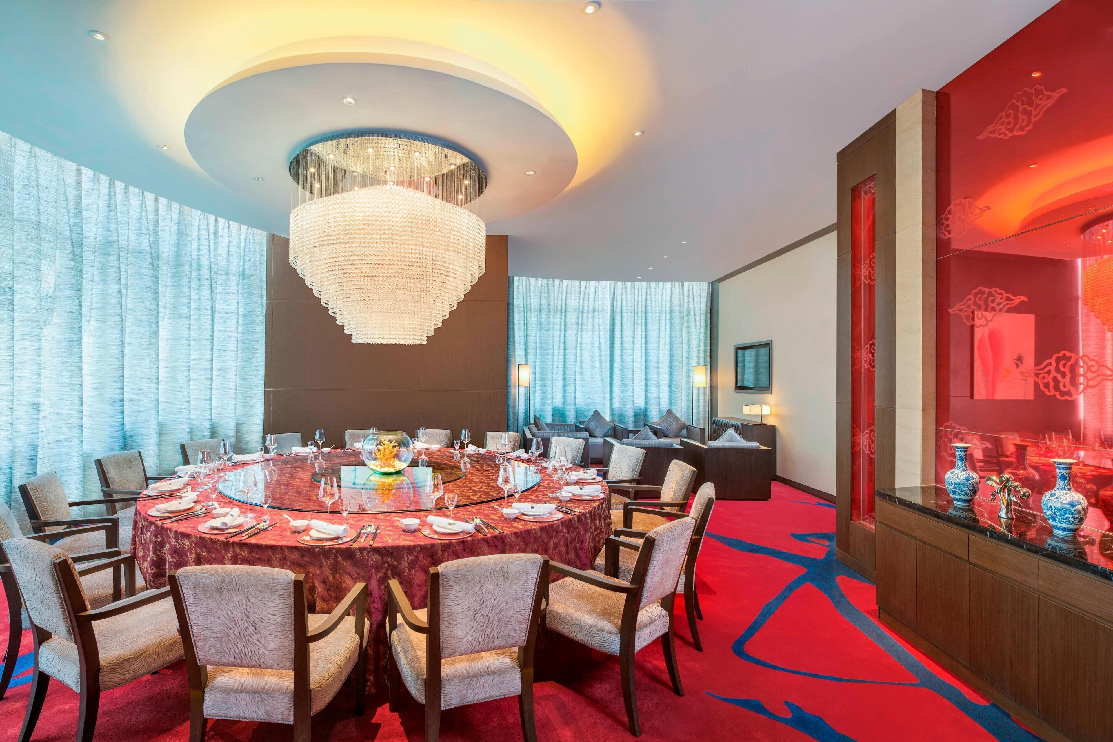 A conference room with a round table, chairs, and a chandelier.