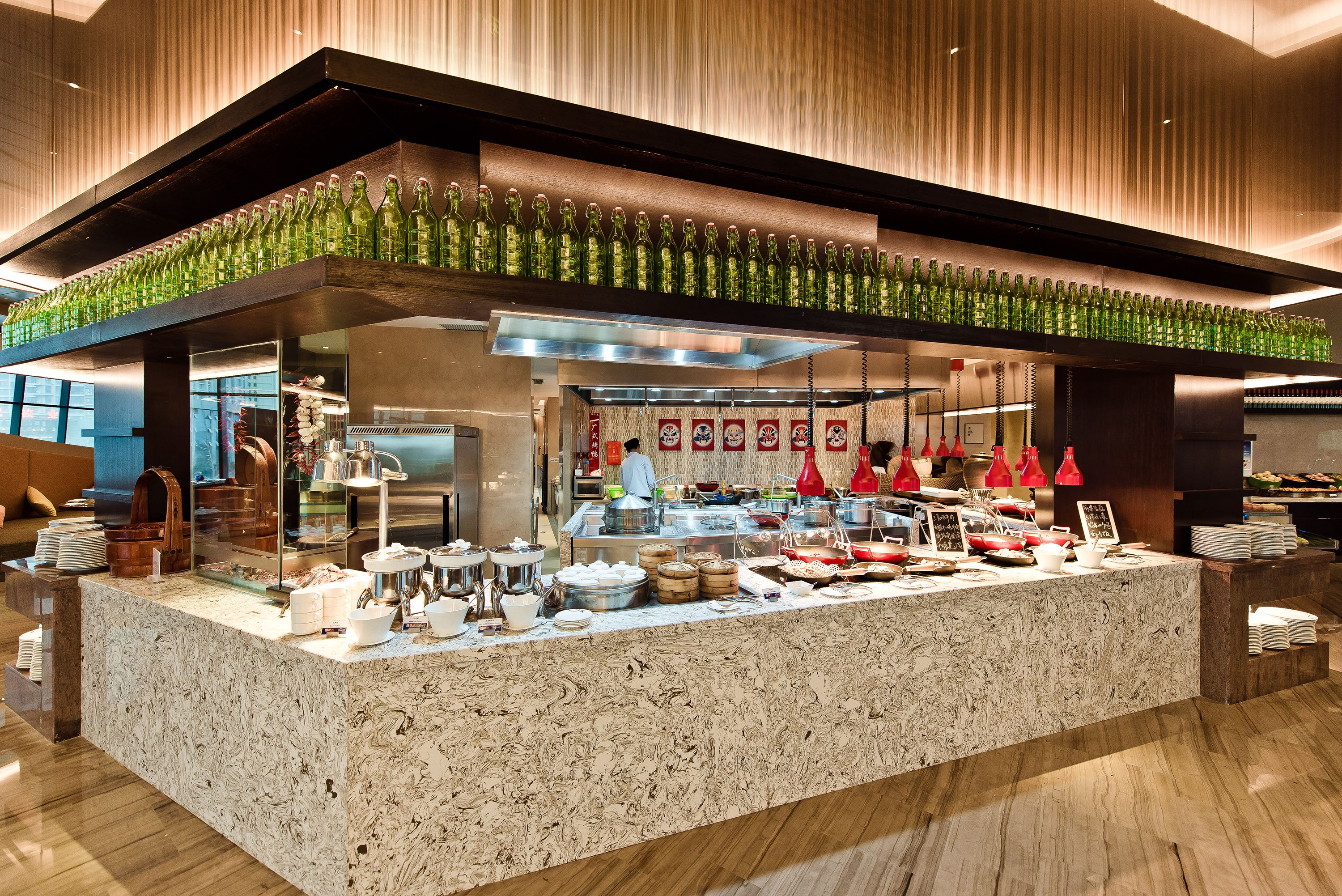 A buffet area with a variety of food items and a display of green bottles.