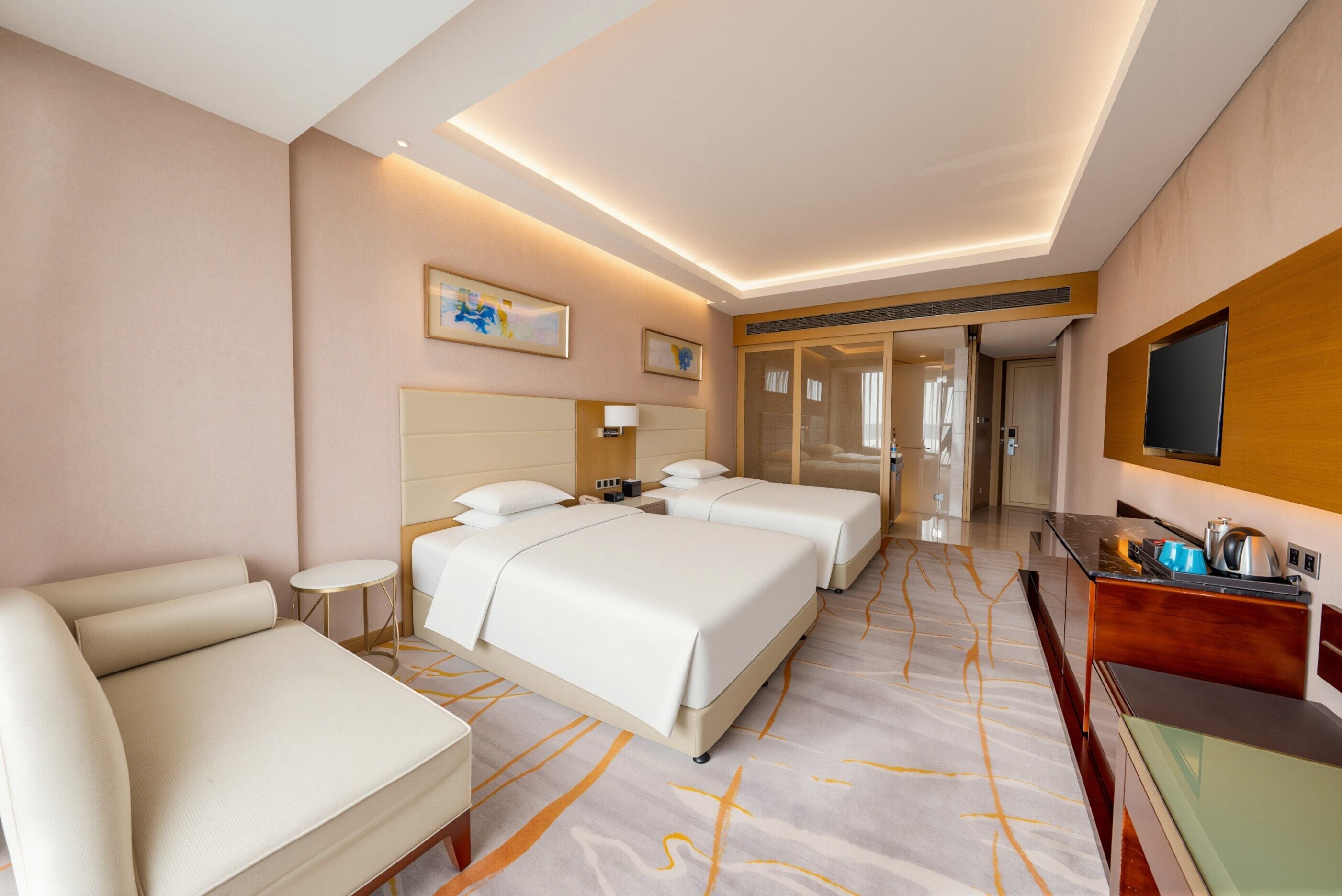 A hotel room with a bed, a sofa, a desk, and a TV.