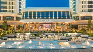 Hôtel Sheraton doté d’une façade moderne, d’une cour intérieure agrémentée d’éléments aquatiques et d’une entrée bien éclairée.