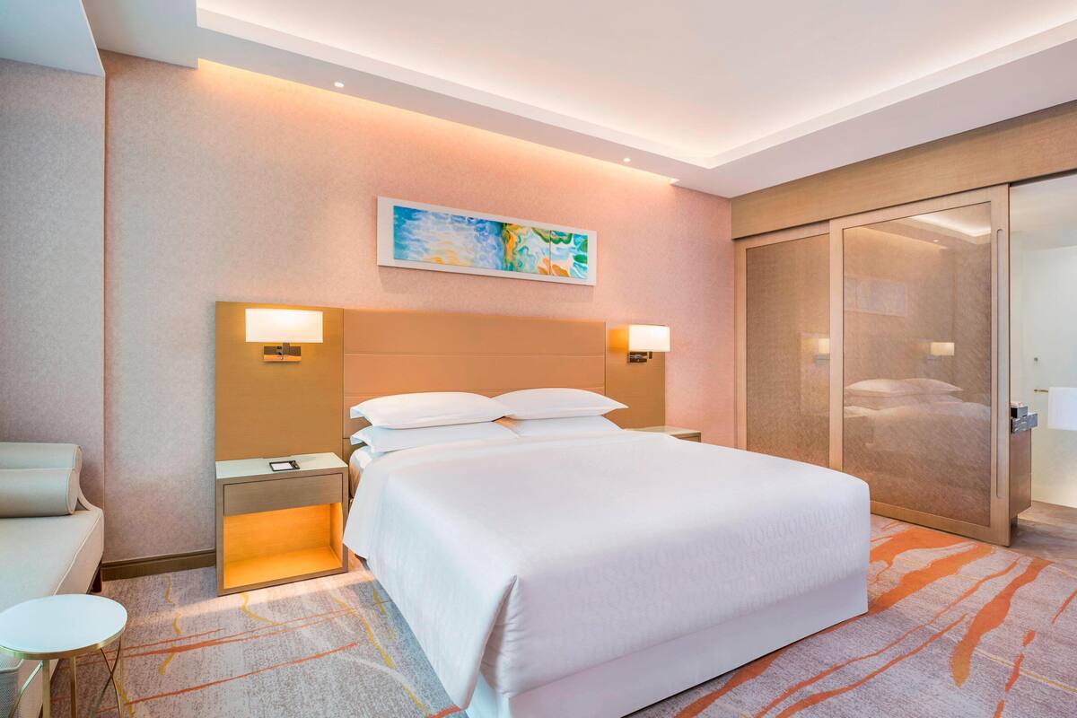Een hotelkamer met een groot bed, nachtkastjes, een bank, een kleine tafel en een schuifdeurkast.
