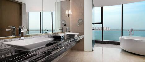 A modern bathroom with a large window, a bathtub, and two sinks.