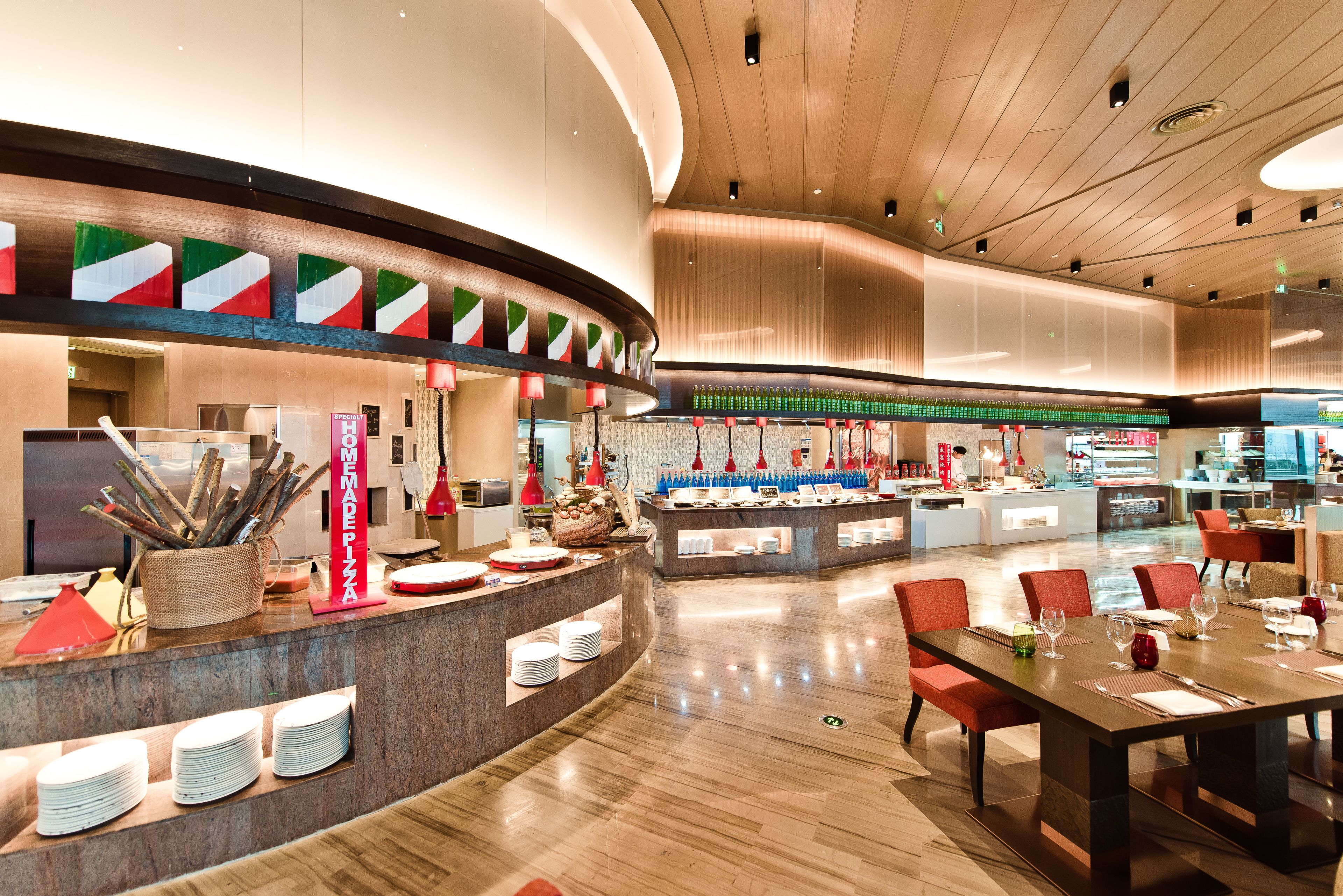 A modern restaurant with a curved counter, multiple seating areas, and a variety of food and drink displays.