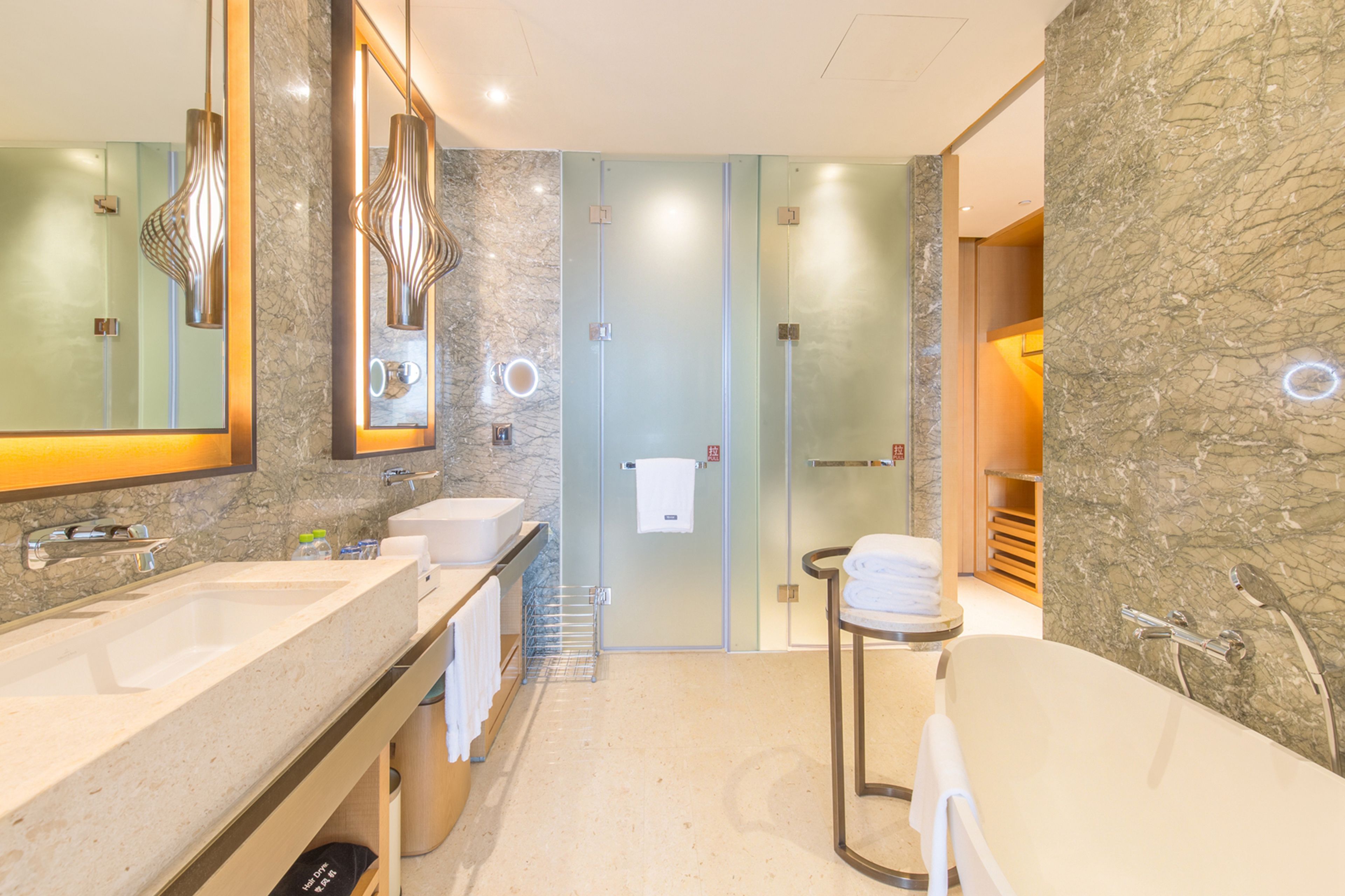A modern bathroom with two sinks, a large mirror, a glass shower enclosure, and a bathtub.