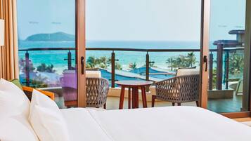 A hotel room with a large window offering a view of the ocean and a pool area.