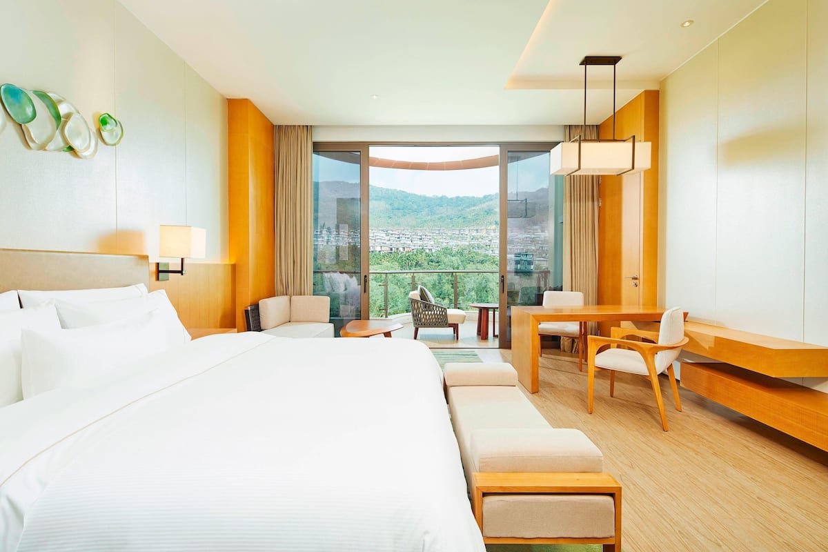 A hotel room with a large bed, a desk, and a view of a cityscape.