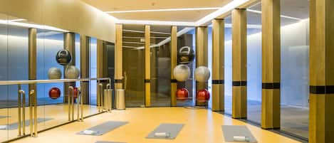 Un gimnasio moderno con colchonetas de ejercicio, un espejo grande y pelotas de fitness.