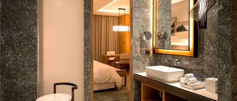 A modern bathroom with a marble sink, a bathtub, and a mirror.