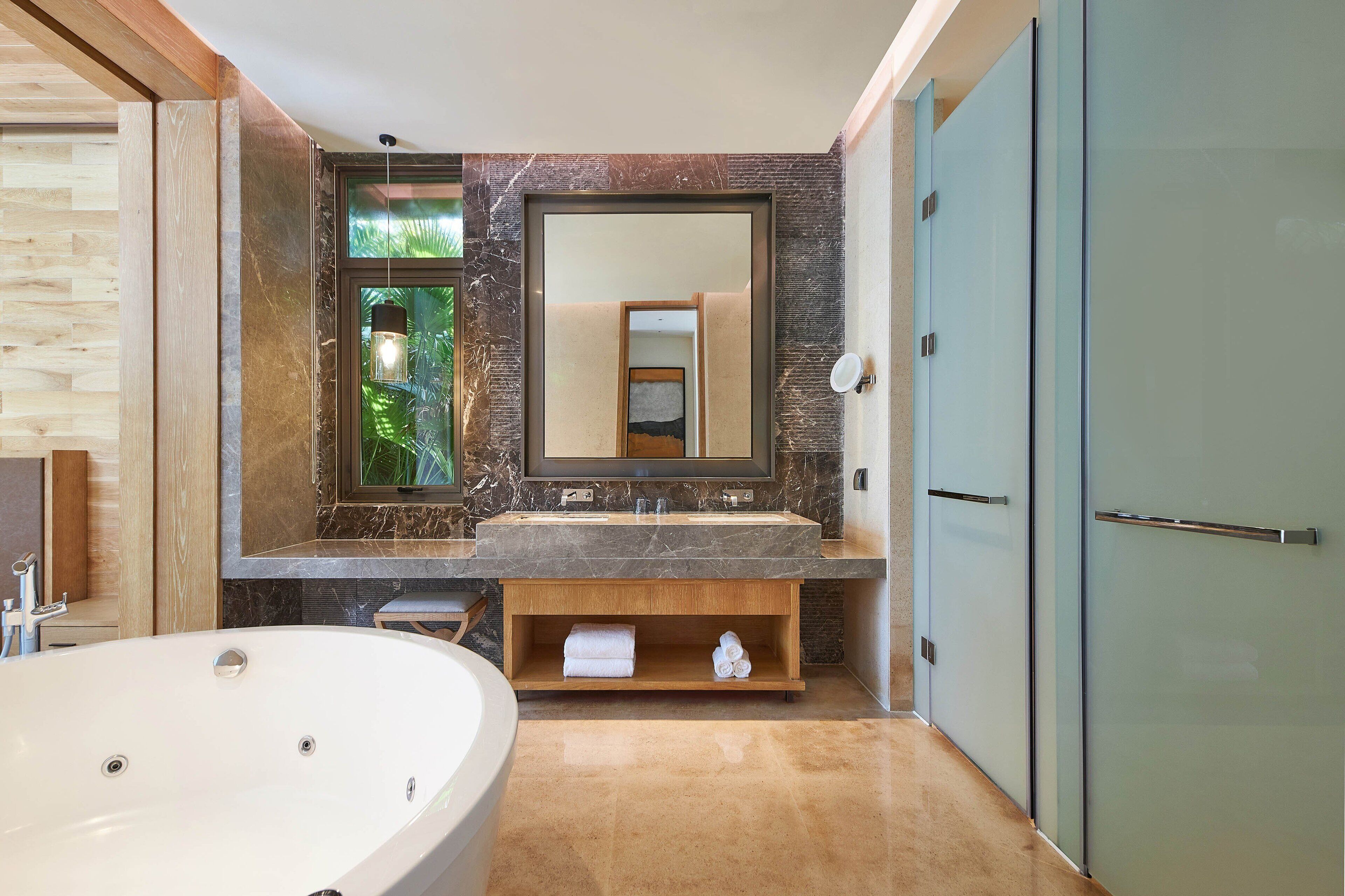 Un baño moderno con una bañera grande, un tocador con encimera de mármol y un espejo amplio.