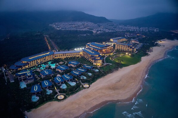 Enjoy stunning ocean views from this beachfront resort, surrounded by a semi-circular layout of buildings and a central pool.