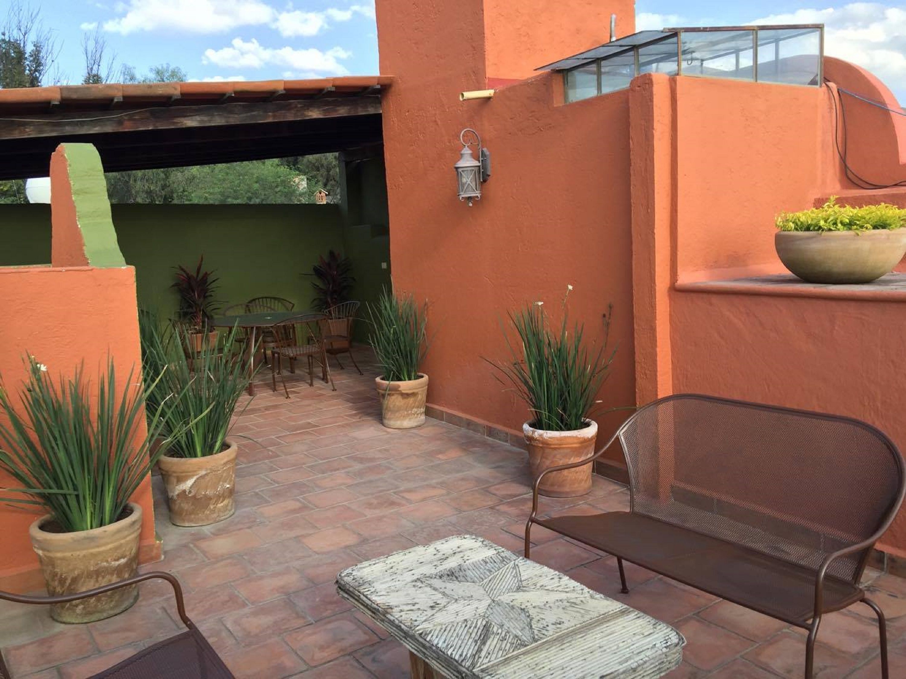 An outdoor patio with a table and chairs, surrounded by potted plants.