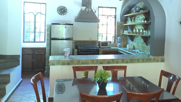 Une cuisine avec un coin repas, comprenant un réfrigérateur, une cuisinière, un four à micro-ondes et une horloge murale.