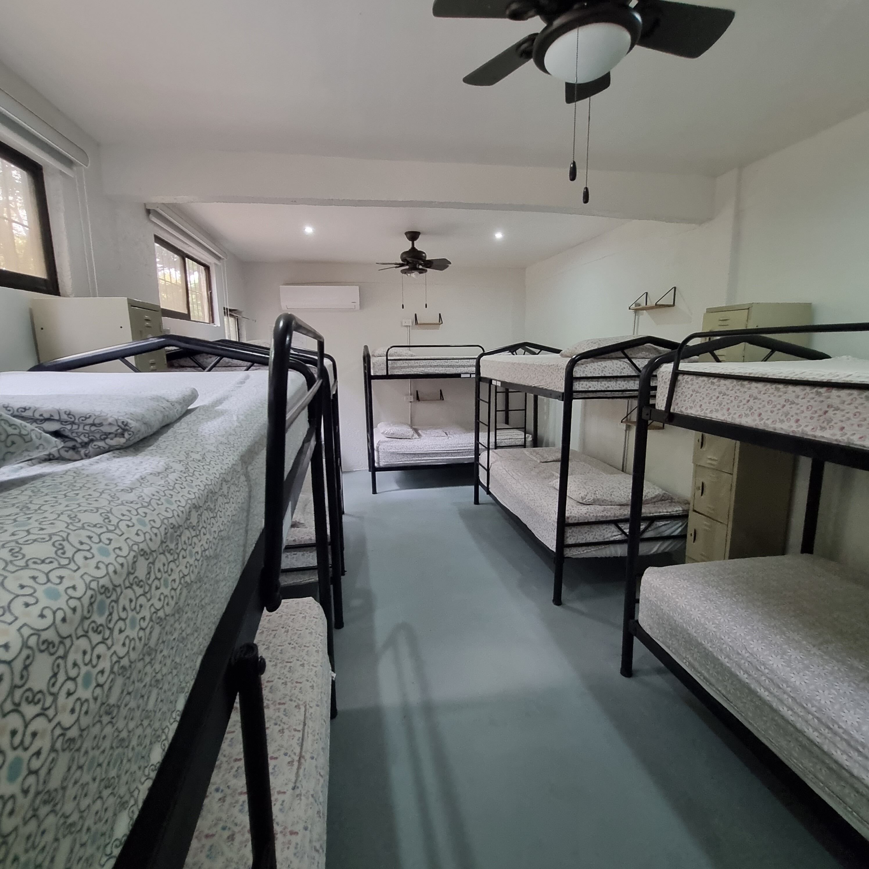 Quarto em dormitório com beliches, ventilador de teto e ar condicionado.