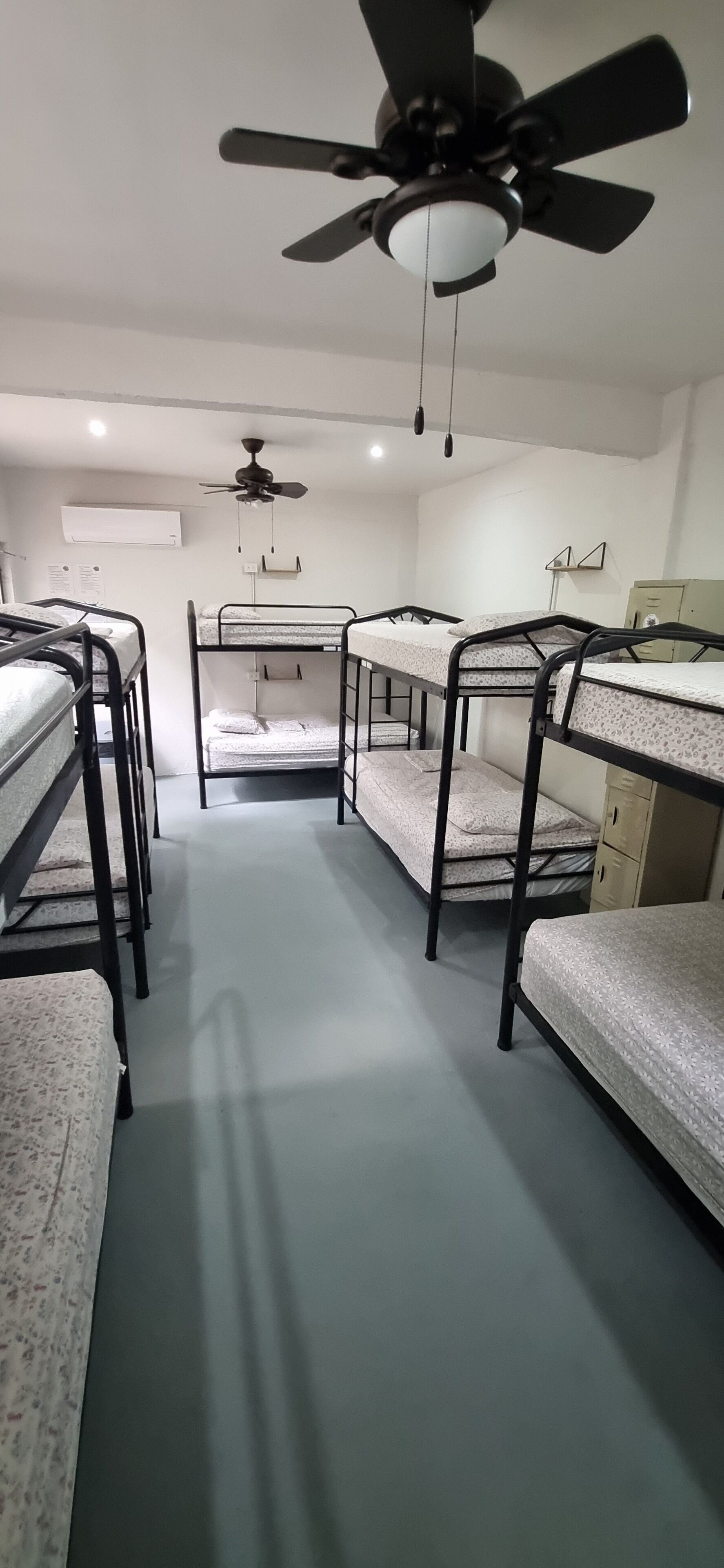 Un dormitorio con literas, ventiladores de techo y un pequeño escritorio con cajones.