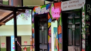 Un interior colorido con un letrero de neón que dice 'Pura Vida' y un cartel sobre las puertas que indica '¡Estás justo donde necesitas estar!'