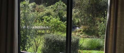 Une pièce dotée d’une grande fenêtre donnant sur un jardin et un paysage vallonné.