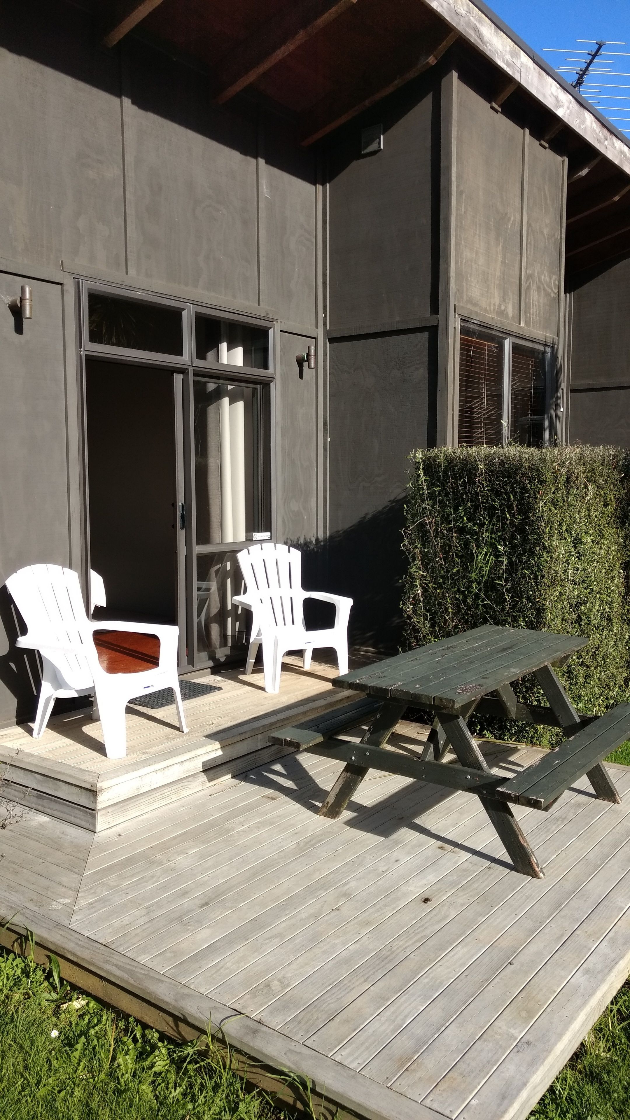 An outdoor deck with two white chairs and a picnic table.