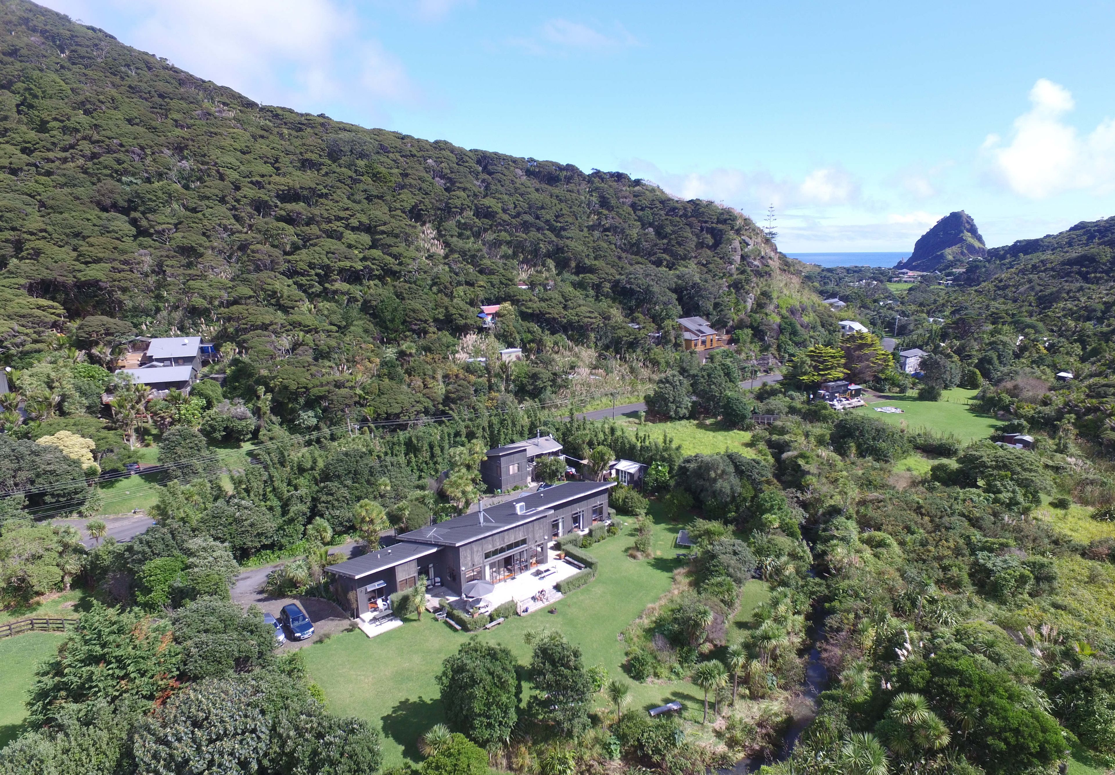 A modern house surrounded by lush greenery and a mountainous landscape.
