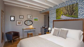 A bedroom with a large bed, a desk with a chair, a mirror, and framed pictures on the wall.