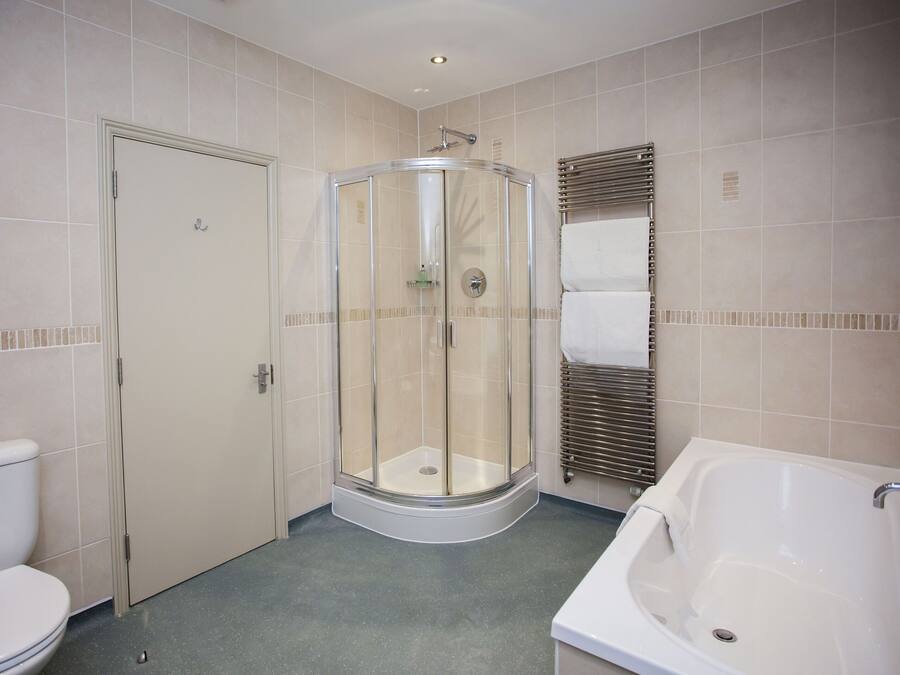 A bathroom with a toilet, a glass-enclosed shower, and a bathtub.