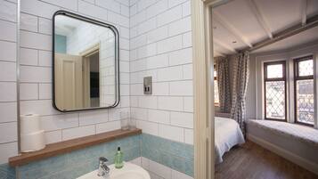 A bathroom with a sink, mirror, and toilet paper.