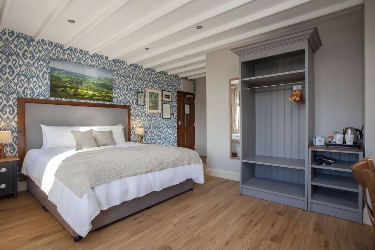 Een slaapkamer met een groot bed, een kledingkast en uitzicht op een landschap door het raam.