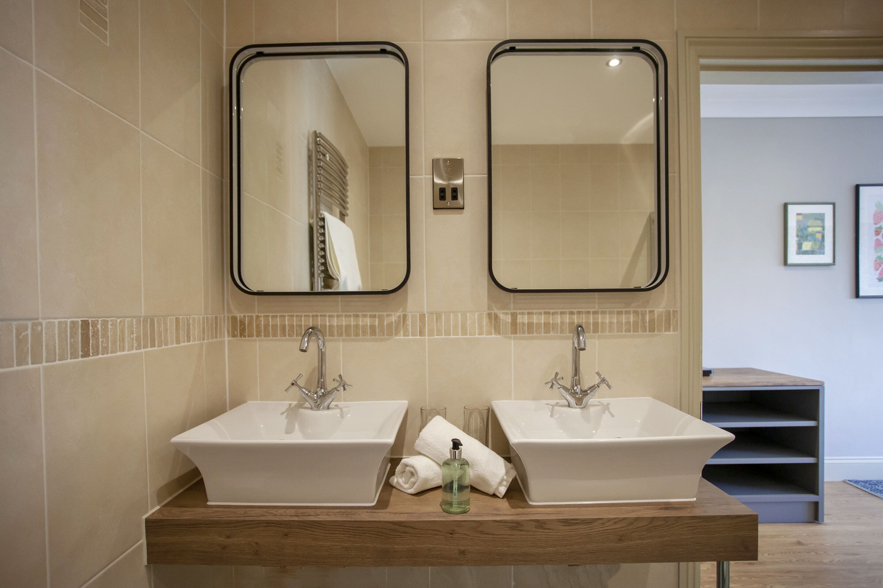A bathroom with two sinks, a wooden vanity, and two mirrors.