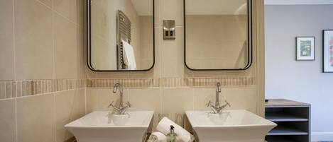 A bathroom with two sinks, a wooden vanity, and two mirrors.