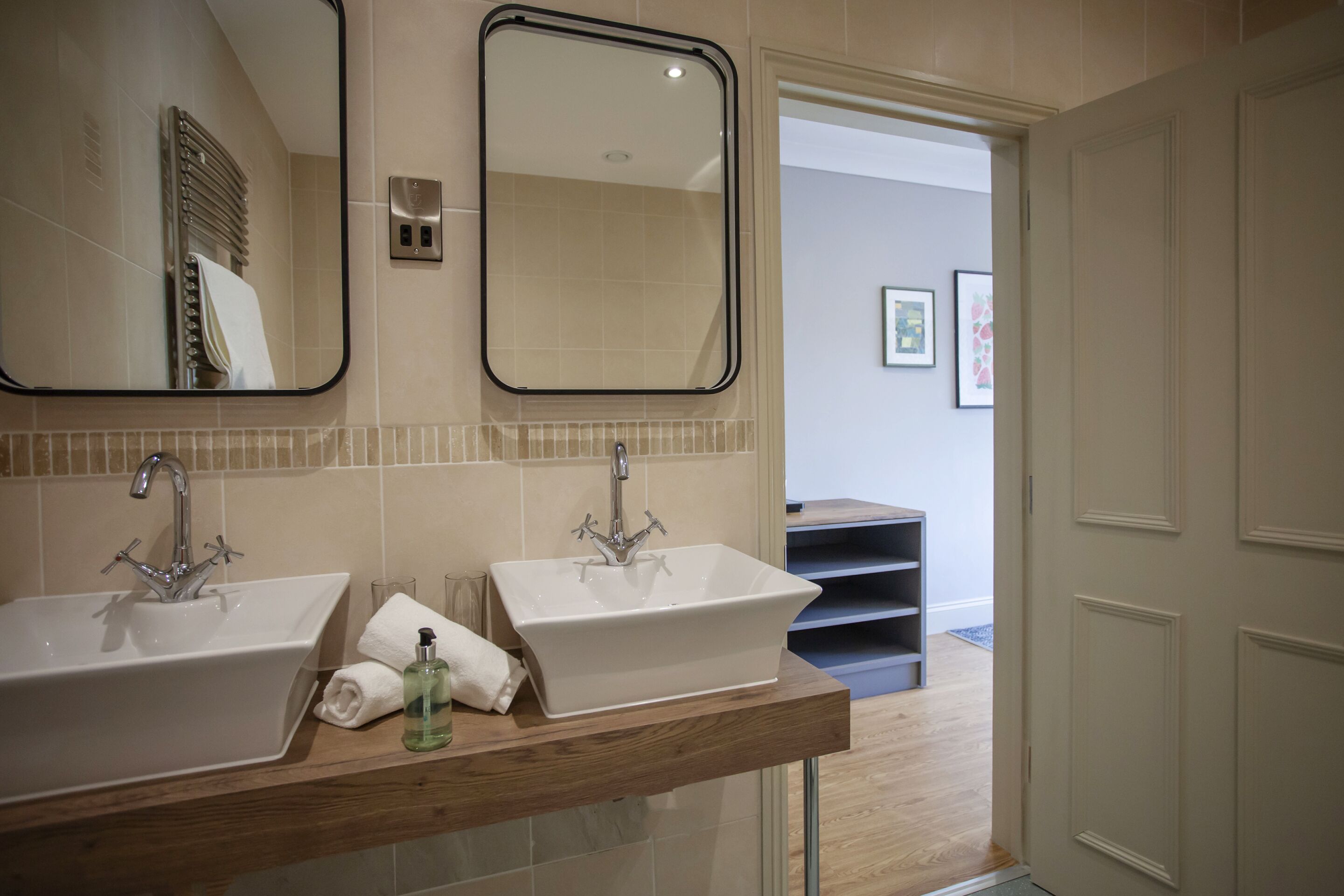 Un baño con dos lavamanos, un espejo y un mueble de tocador de madera.