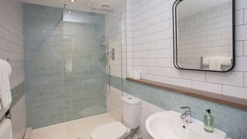 A bathroom with a shower, toilet, sink, and mirror.