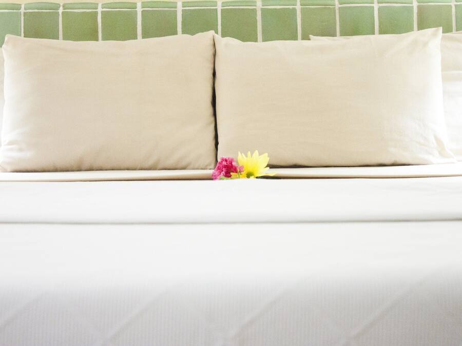 Un lit avec deux oreillers beige et une seule fleur.