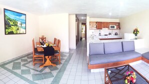 A living room with a sofa, a dining table with chairs, a kitchen area, and artwork on the walls. - Coral Ixtapa (Ixtapa)