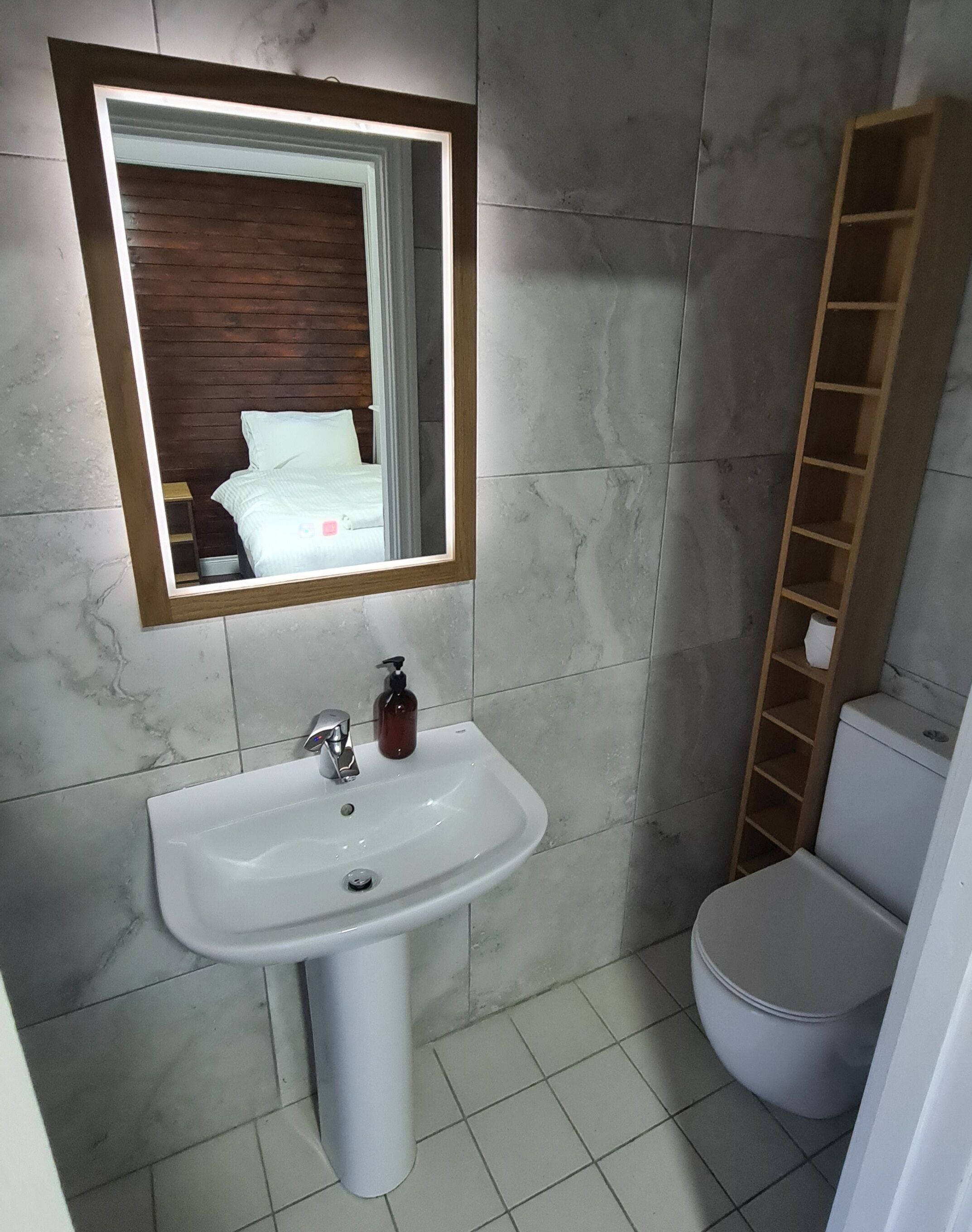 Een badkamer met een wit wastafelmeubel, een spiegel en een toilet.