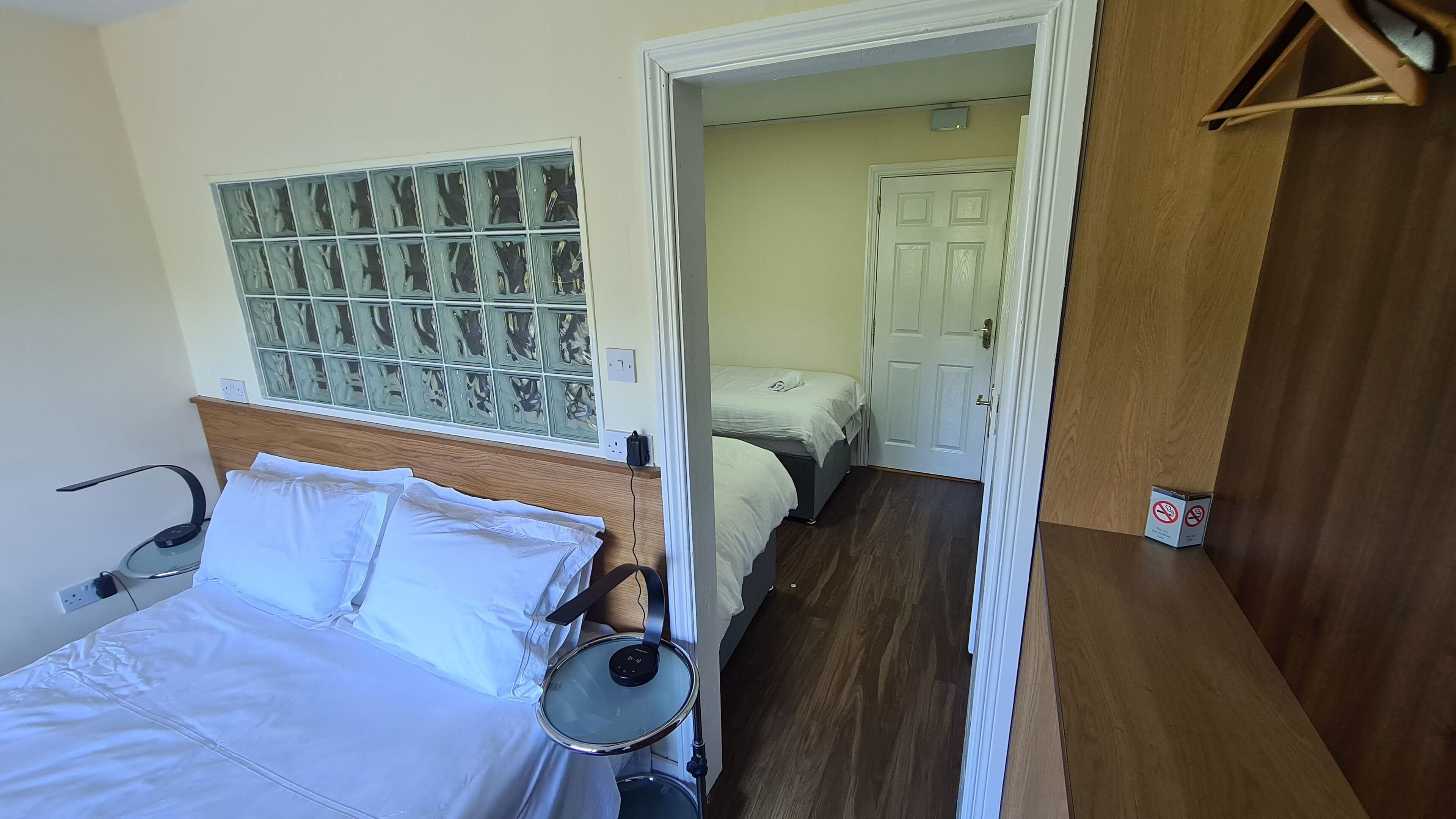 A hotel room with a bed, bedside table, and a wall-mounted coat rack.