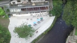 A modern hotel with a glass balcony, outdoor seating, and a river view. - The Meetings B&B (Avoca)
