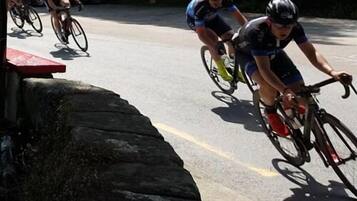 A group of cyclists on a paved road with a stone wall on one side.