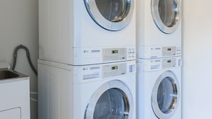 Une buanderie équipée de deux machines à laver à chargement frontal superposées et d’un seul sèche-linge.