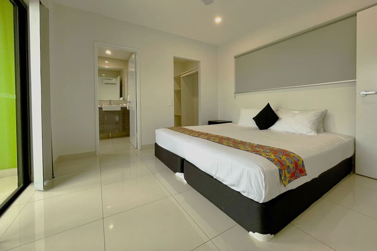 A modern hotel room with a large bed, a ceiling fan, and a bathroom visible through an open door.