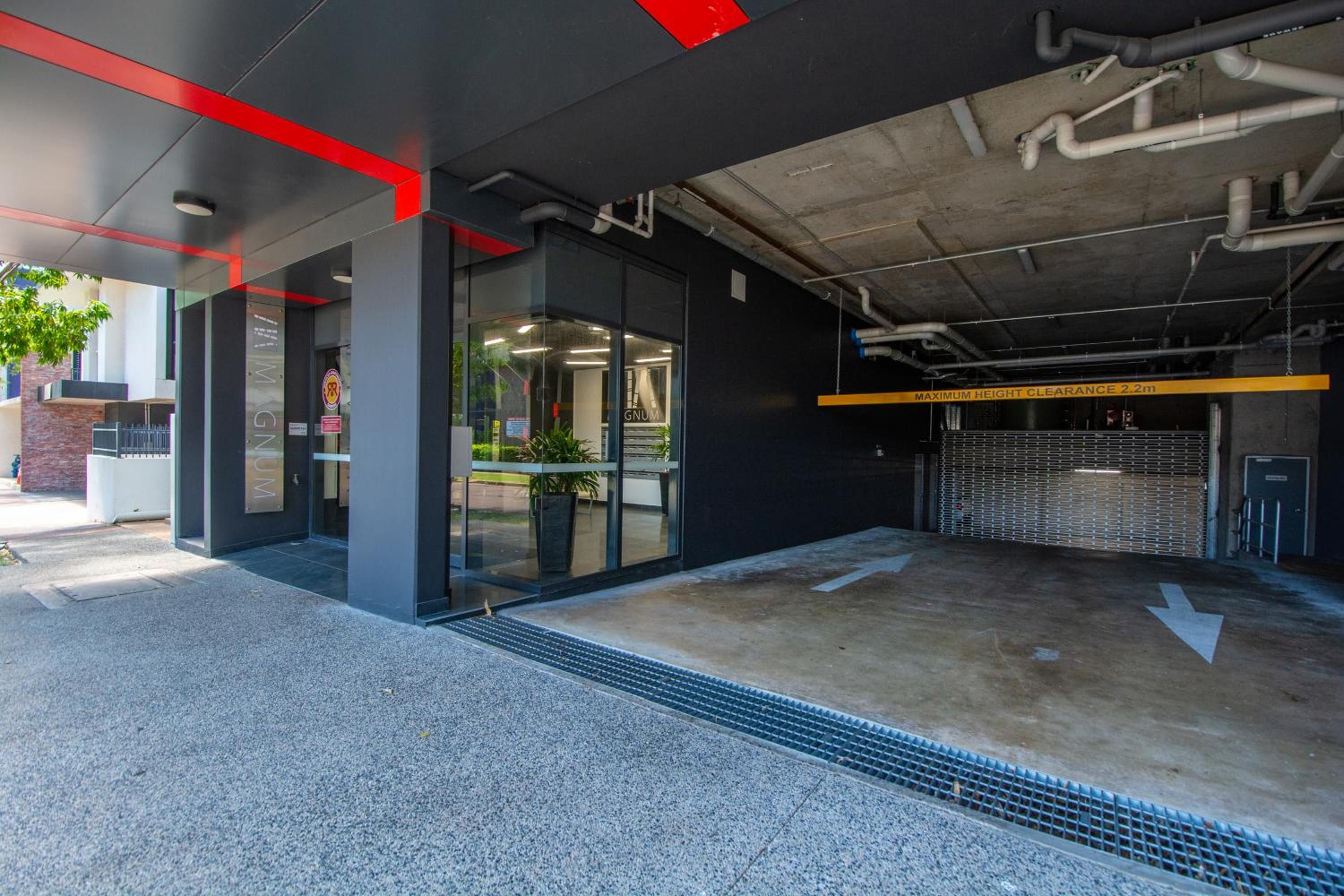 Eine moderne Tiefgarage mit Höhenbeschränkungshinweis, einem Metallgittereingang und einem Betonboden.