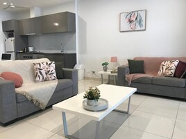 Una sala de estar moderna con dos sofás, una mesa de centro y una cocina al fondo.