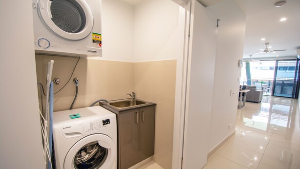 Un espace buanderie compact comprenant un lave-linge, un évier et un meuble de rangement.