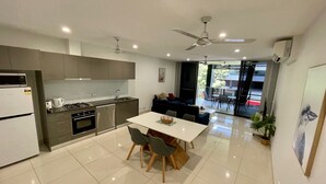 A modern kitchen with a dining area, a ceiling fan, and a view to the outside. - Magnum Serviced Apartments (Darwin)