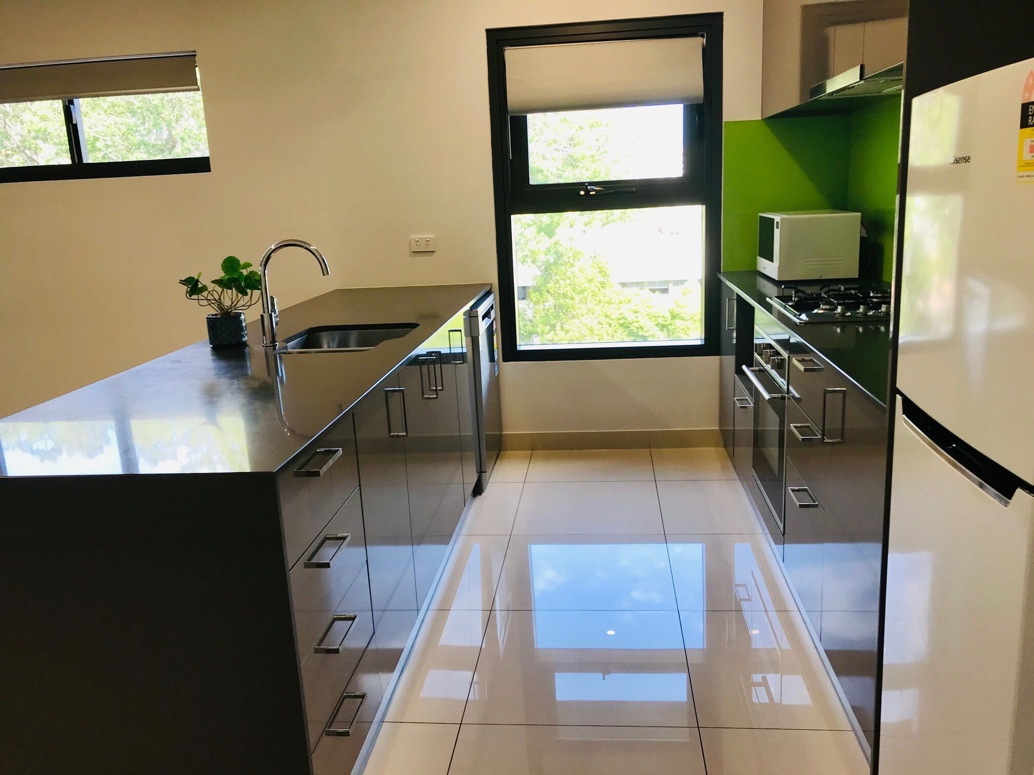A modern kitchen with a large window, stainless steel appliances, and a potted plant.