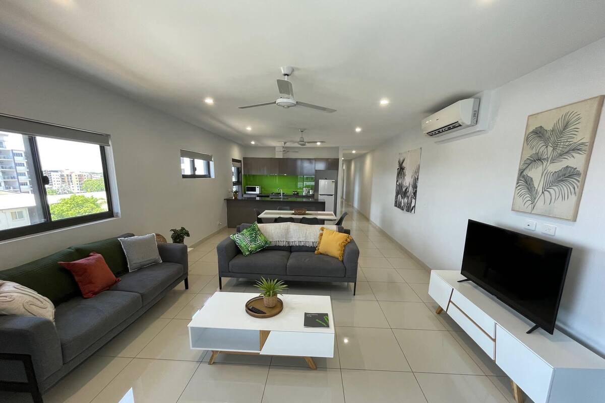 A modern living room with a grey sofa, a white coffee table, and a flat-screen TV.
