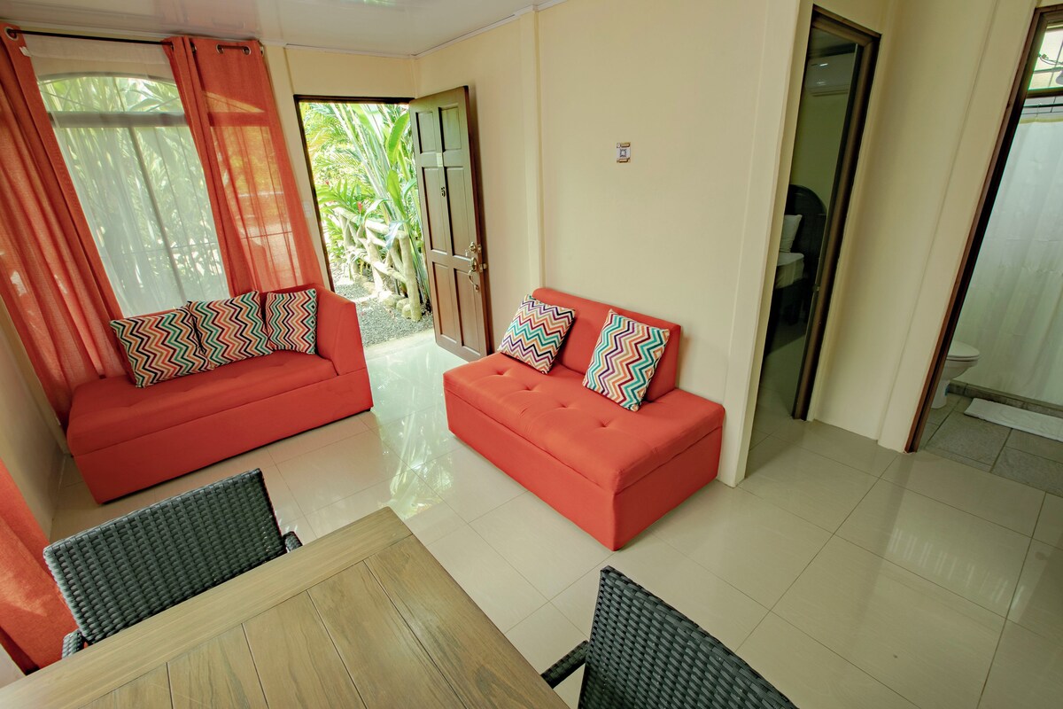 Una habitación con un sofá rojo, una mesa de madera y una silla.