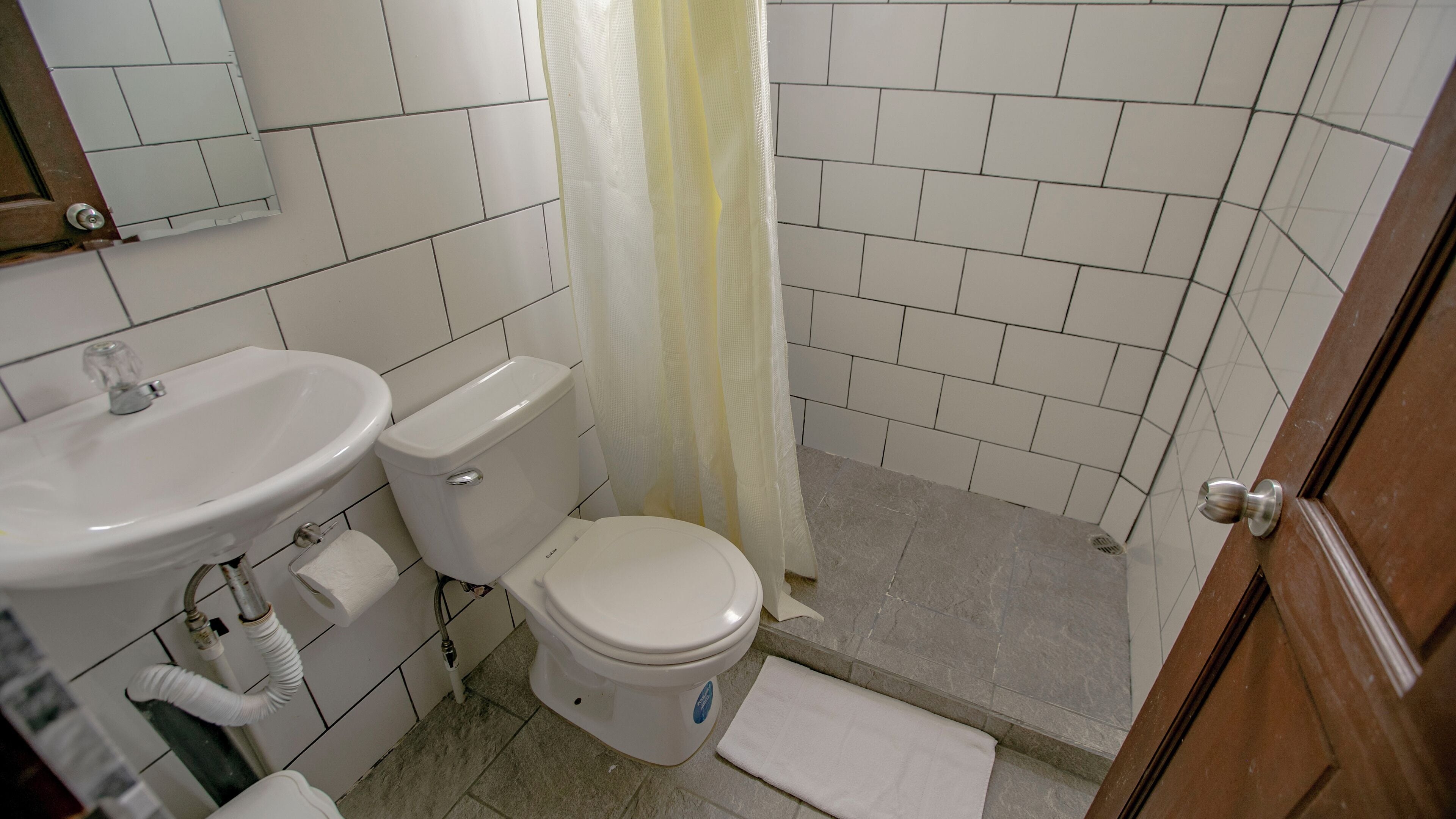 A bathroom with a white sink, toilet, and shower curtain.