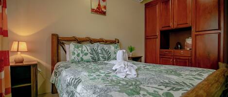 Un dormitorio con cama, mesita de noche, lámpara, planta en maceta y armarios de madera.