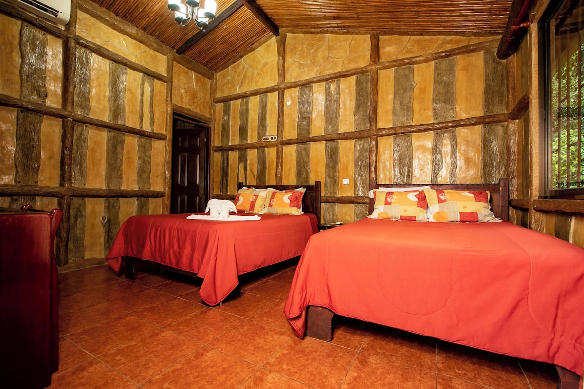 A room with two beds, wooden walls, and a tiled floor.