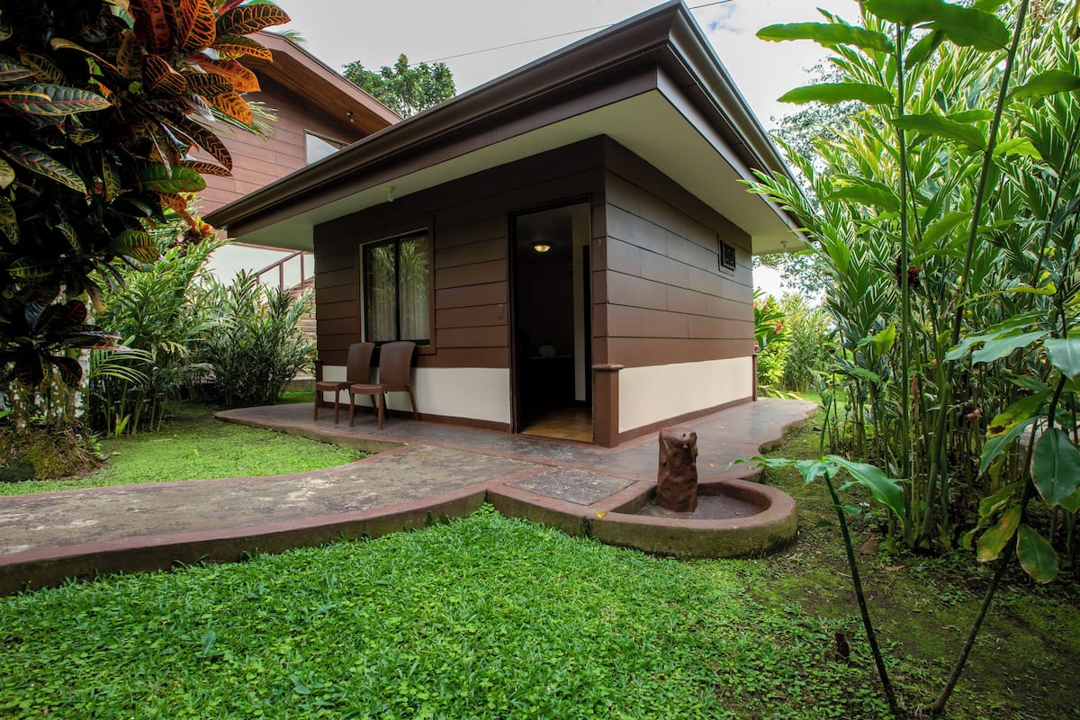 A modern house with a covered porch, a small garden, and a pathway leading to the entrance.